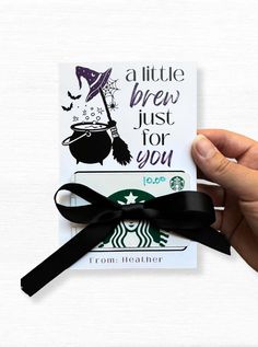 a hand holding a starbucks card with a black bow on it's side and the words, a little brew just for you