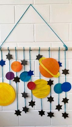 a wall hanging made out of paper with stars and planets attached to the side of it