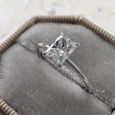 an engagement ring with a princess cut diamond in it on a cushioned velvet case