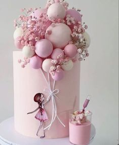 there is a pink cake with balloons on it