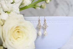 Dainty yet glamorous, The Rose Earrings in Gold, are the perfect accessory to accent a bateau neckline for both you and your bridesmaids. The subtle sparkle adds a touch of elegance to your wedding day look. Size: 1.5" long Materials: cubic zirconia, Swarovski pearls in white Metals: gold filled ear wires and components Find the matching necklace here Elegant Rose Gold Bridal Earrings For Wedding, Elegant Bridal Accessories For Anniversary, Elegant Crystal Earrings For Wedding, Elegant Drop Earrings For Anniversary Bridal Accessories, Elegant Crystal Bridal Earrings For Wedding, Classic Rose Gold Bridal Earrings For Wedding, Elegant Bridal Drop Earrings For Anniversary, Elegant Crystal Bridal Accessories For Anniversary, Elegant Anniversary Bridal Drop Earrings