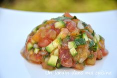 a white plate topped with cucumber, tomato and avocado salad on top of it