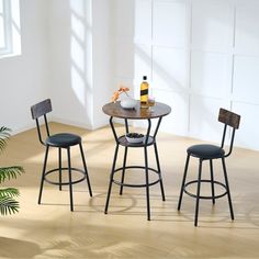 three chairs and a table in a room with white walls, wood floors and flooring