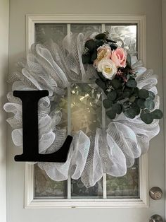 a white mesh wreath with the letter j hanging on it's front door window