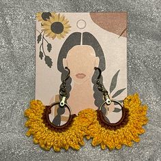 a pair of sunflower earrings with a woman's face on it