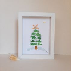 a white frame with a green and orange christmas tree on it next to a shell