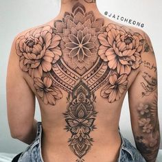 the back of a woman's body with tattoos and flowers on her upper half