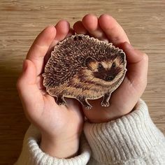 a person holding a small hedgehog sticker in their hands