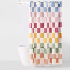 a colorful shower curtain hanging next to a bathtub with a white toilet in front of it