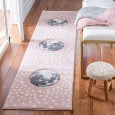 a pink rug with stars and the moon on it in front of a white chair