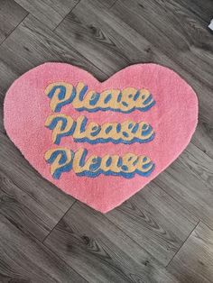 a pink heart shaped rug with the words play please please written in blue on it