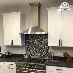 a stove top oven sitting inside of a kitchen next to white cabinets and counter tops