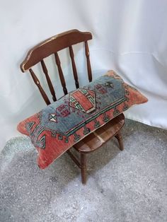 an old chair with a pillow on it sitting in front of a white wall and floor