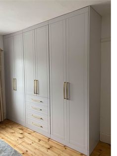 an empty room with white cabinets and wood flooring on one side, two gold handles on the other