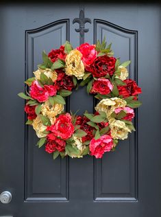 a wreath with red and yellow flowers is hanging on the front door's black door