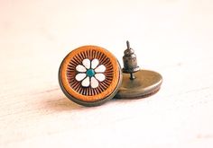 a wooden button with a flower on it sitting on top of a white table next to a screw