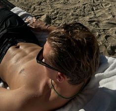 a man laying on top of a beach next to a white frisbee in his hand