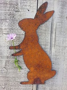 a metal rabbit with a flower in it's mouth sitting on a wooden surface