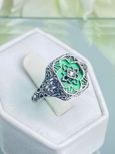 Emerald Green Glass with Cubic Zirconia Ring Cathedral Design#D204 This is a lovely detailed and intricate Art Deco reproduction ring. This lovely filigree reproduction ring is handcrafted in sterling silver. The lovely emerald green glass is 11mm x 9mm. The face of the ring is 13.5mm North South and 10mm East West on the finger. Notice the 1.5mm center White CZ gemstone. The inside of the band is marked 925 for sterling silver. This is an exquisite rendition of an antique filigree ring. The intricate and detailed design of the filigree setting travels all the way down the band of the ring. The ornate curves create a design that is majestic and regal just like the cathedrals of old. This ring is a beautiful vintage look that will created a graceful image suitable for any occasion. Heirloom Emerald Ring With Intricate Design For Anniversary, Green Filigree Ring For Anniversary, Vintage Enamel Ring With Rose Cut Diamonds For Gift, Antique Green Diamond Ring For Anniversary, Vintage Enamel Ring With Rose Cut Diamonds As Gift, Hallmarked Green Enamel Ring For Anniversary, Vintage Green Enamel Ring For Anniversary, Ornate Green Jewelry With Intricate Design, Green Hallmarked Enamel Ring For Anniversary