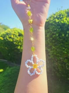 a person's arm with a bracelet made out of beads and flowers on it