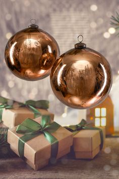 two shiny gold christmas balls with bows and presents