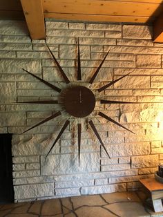 a clock mounted to the side of a brick wall next to a fire place in a living room