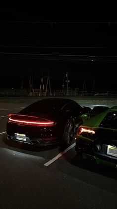 two sports cars parked in a parking lot at night with their lights on and the headlights turned on