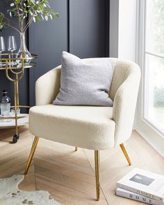 a chair with a pillow on it in front of a window next to a book