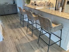 four chairs are lined up in front of the kitchen counter and bar stools that sit at the end of the island