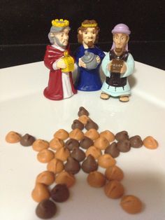 three figurines are sitting on a plate with nuts in the shape of a star