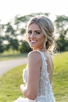 a beautiful woman in a white dress posing for a photo with trees in the background