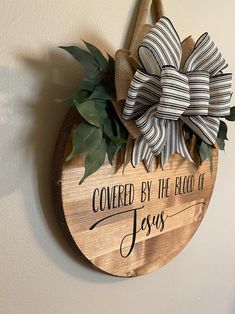 a wooden sign that says covered by the blood of jesus hanging on a white wall