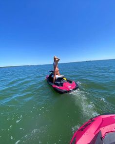 a woman riding on the back of a pink jet ski