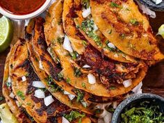 several tortillas stacked on top of each other next to salsa and limes