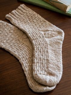 a pair of socks sitting on top of a wooden table next to a book and an open book