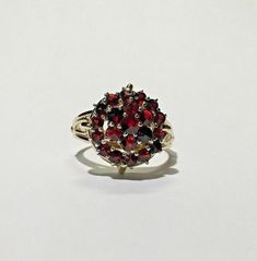 Estate Victorian Bohemian Garnet 2 Tiered Split Shank 14k YG & Silver Ring Size 7Metal: 14k yellow gold, stampedsilver top, acid testedWeight: 4.4 gramsRing size: 7 (can be resized upon request)Size: Center is 16mm in diameter (at widest point)Shank tapers from 6.50mm to 4mm to 2.25mm on bottomStones: (1) 3.35mm center garnet,(6) 2.80mm garnets (one is slightly chipped),(14) 2.25mm garnetsHallmarked: 14kThis is an estate piece in excellent condition.  Please see pictures for reference. Antique Gold Cluster Ring With Gemstones, Antique Multi-stone Yellow Gold Cluster Ring, Antique Multi-stone Cluster Ring In Yellow Gold, Antique Gold Cluster Ring With Multi-stone, Antique Yellow Gold Cluster Ring With Gemstone, Cluster Yellow Gold Hallmarked Rings, Heirloom Yellow Gold Round Cluster Ring, Yellow Gold Cluster Rings Hallmarked, Yellow Gold Cluster Ring With Hallmark