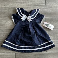 Size 3t Blue With White Striping Accents Sailor Dress Style. Comes With Matching Hat. New With Tags Preppy Navy Cotton Dress, Blue Sailor Cotton Dress, Blue Cotton Sailor Dress, Blue Sailor Style Cotton Dress, Sailor Style Blue Cotton Dress, Cute Navy Dress For Dress-up Occasions, Navy Fitted Cute Dress, Cute Navy Short Sleeve Dress, Cute Fitted Navy Dress