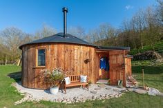 a small wooden building with a bench in the front and side yard area next to it