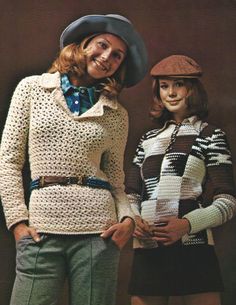 two women standing next to each other wearing sweaters and hats