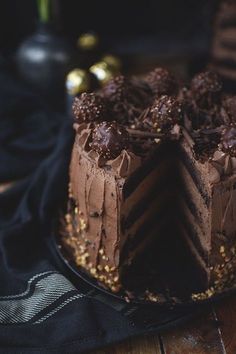 a chocolate cake on a black plate with gold sprinkles and two slices missing