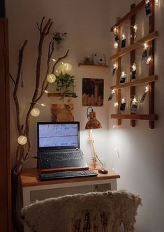 a laptop computer sitting on top of a wooden desk next to a tree with lights