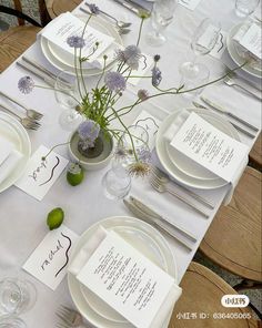 the table is set with place cards and flowers in vases on top of each plate