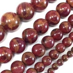 red and brown beads are lined up on a white surface, with one bea in the middle