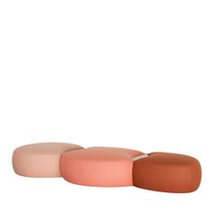 three different colored stools sitting next to each other on a white surface, one with an orange and the other pink