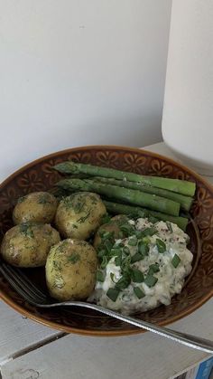 a brown bowl filled with potatoes and asparagus