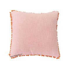 a pink pillow with orange pom poms on it