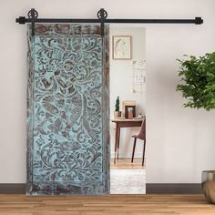 an open door with intricate designs on it in front of a wooden table and chair