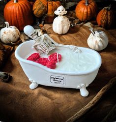 a skeleton in a bathtub with pumpkins and other halloween decorations around it on a table