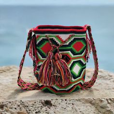 Introducing our exquisite Handmade Crochet Wayuu Bag, a stunning blend of tradition and contemporary style. Handcrafted by skilled artisans from the indigenous Wayuu community in Colombia, each bag is a masterpiece of intricate weaving and vibrant colors. With a diameter ranging from 9 to 13 inches and a matching depth, this bag strikes the perfect balance between functionality and elegance. Its compact yet spacious design allows you to carry your essentials with ease while adding a touch of uni Multicolor Handwoven Bucket Bag As A Gift, Traditional Multicolor Handwoven Bucket Bag, Traditional Handwoven Multicolor Bucket Bag, Traditional Multicolor Woven Bucket Bag, Traditional Multicolor Handmade Bucket Bag, Traditional Multicolor Bucket Bag, Traditional Handmade Multicolor Bucket Bag, Traditional Multicolor Bucket Bag For Daily Use, Traditional Multicolor Crochet Bag As Gift