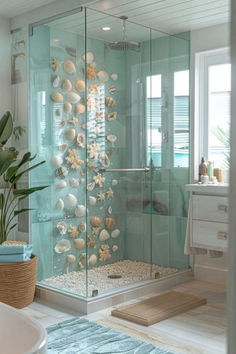 a bathroom with a glass shower door and sea shells on the wall in front of it